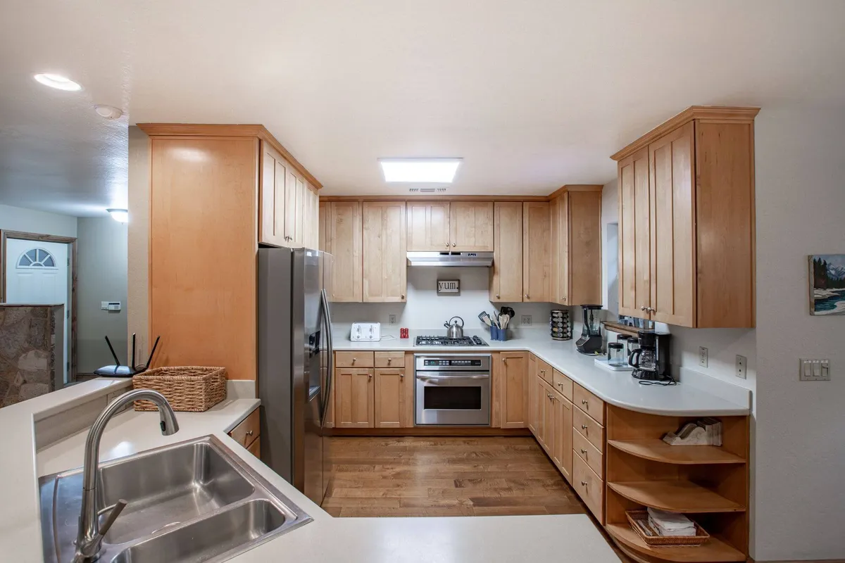 A spacious kitchen featuring modern stainless-steel appliances, warm wood cabinetry, and an open layout. Generous counter space invites culinary activity, while the kitchen island allows for both meal prep and casual gathering. The room is filled with natural light, making it ideal for social cooking and sharing meals.