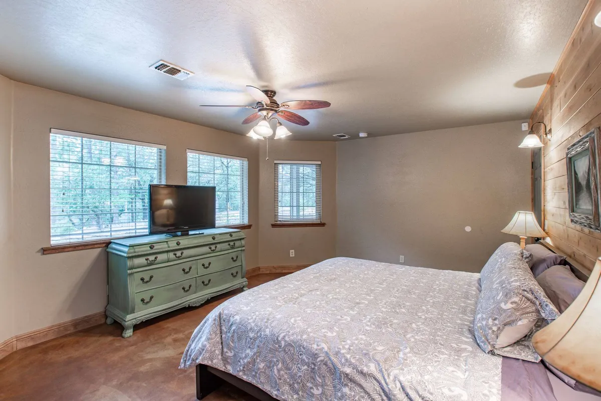 A bright, inviting bedroom with a large bed, dresser, and windows letting in natural light. The room feels restful and organized, designed for relaxation after a day outdoors.